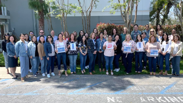 Group photo of employees wearing denim and holding support survivor signs