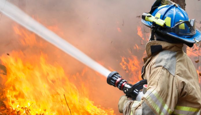 Photo of fire and firefighter spraying water at it