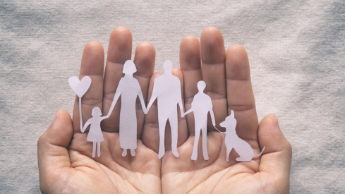 Photo of hands holding cutout images of a family